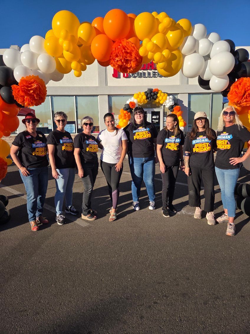 Group of people in front of a building with balloon arch. They are wearing matching shirts. Sunny outdoors.