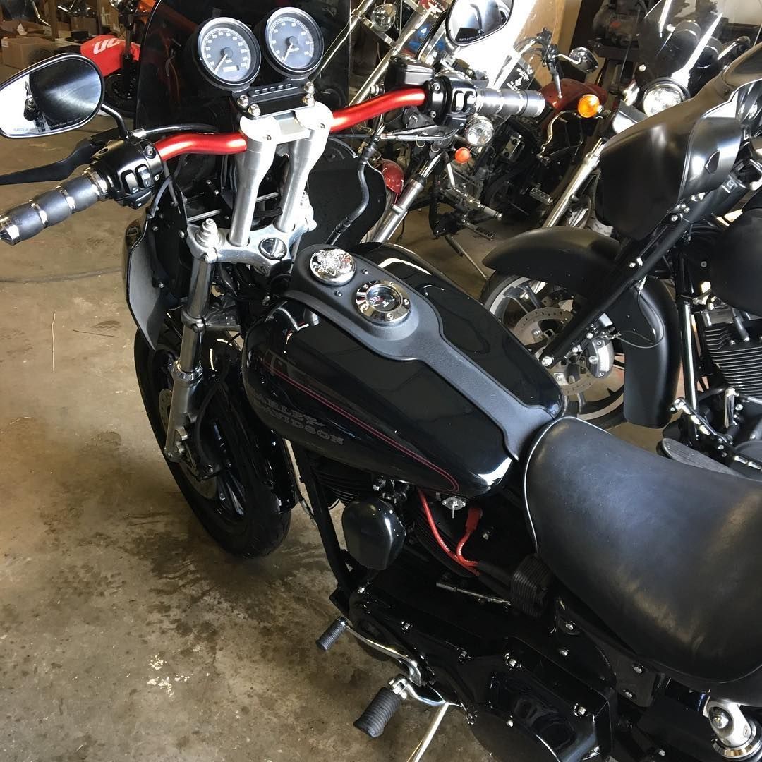 Black motorcycle with red handlebars, parked indoors.