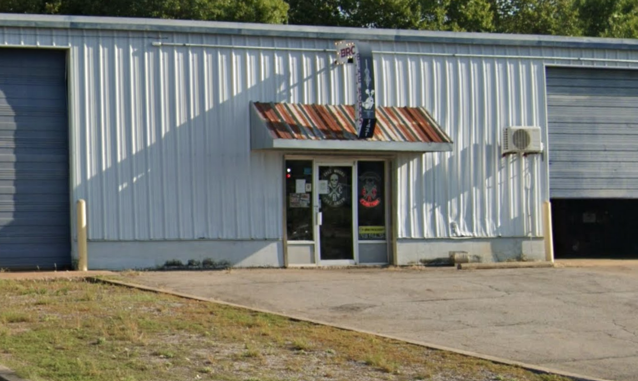 Two motorcycles parked in front of a Harley-Davidson shop with a metal awning on a sunny day.