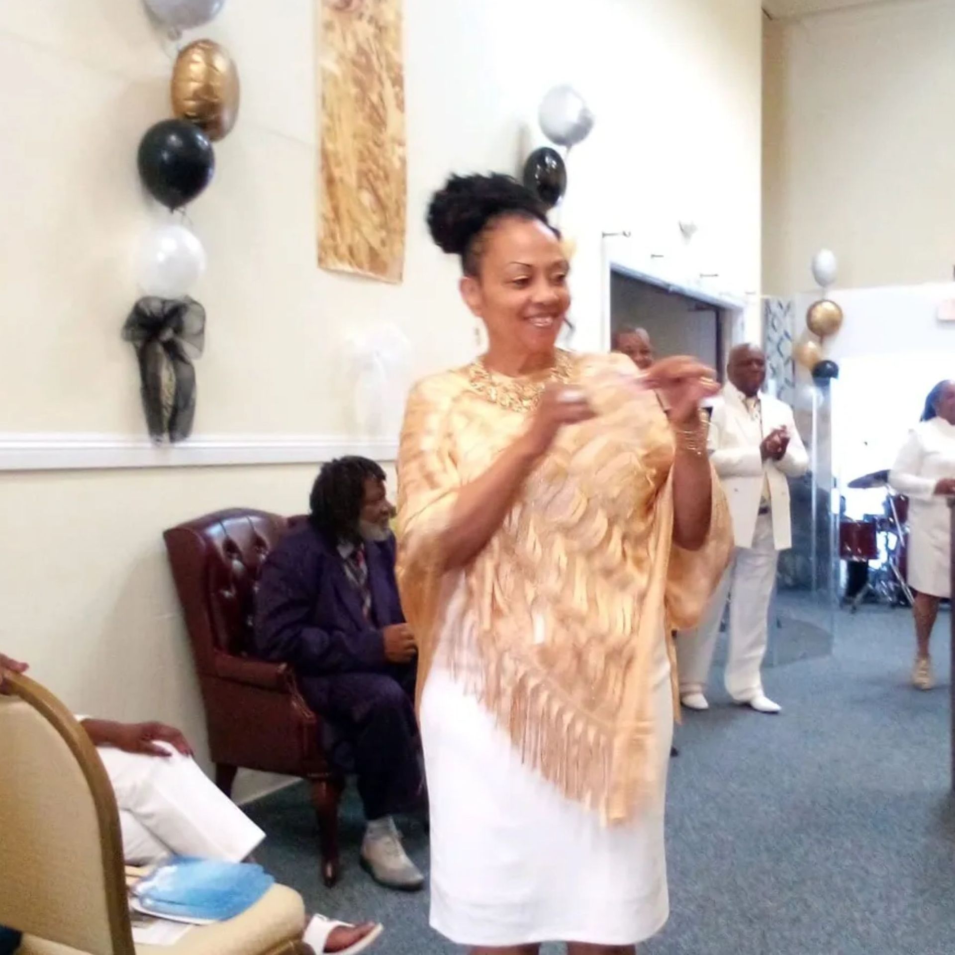 A woman in a white dress is standing in a room with balloons on the wall