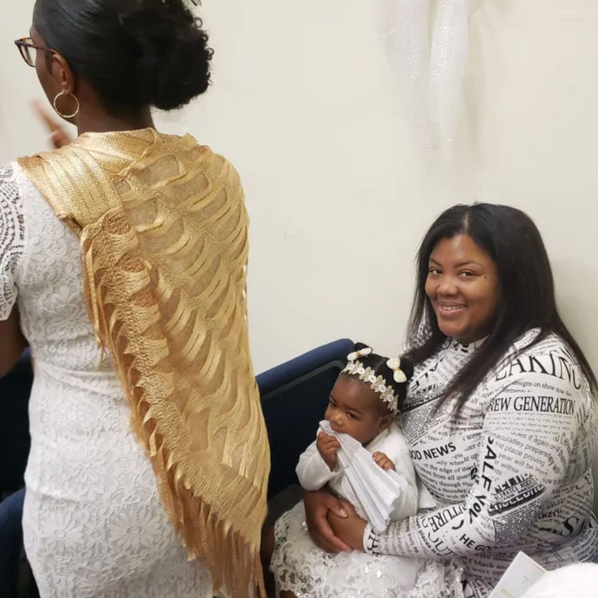 A woman in a newspaper shirt is holding a baby