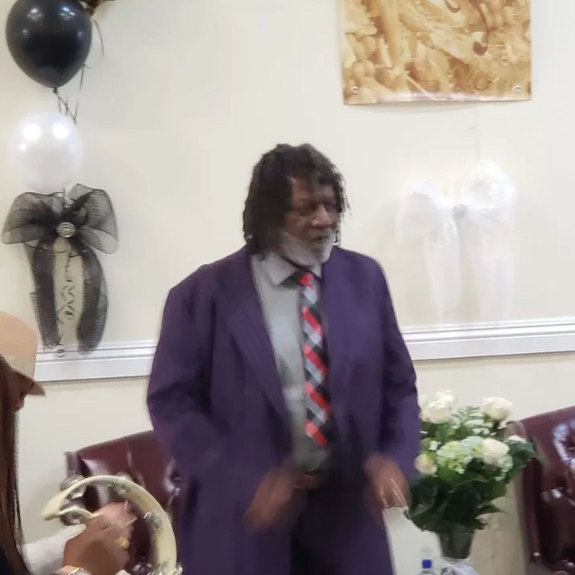 A man in a purple suit and tie is standing in a room