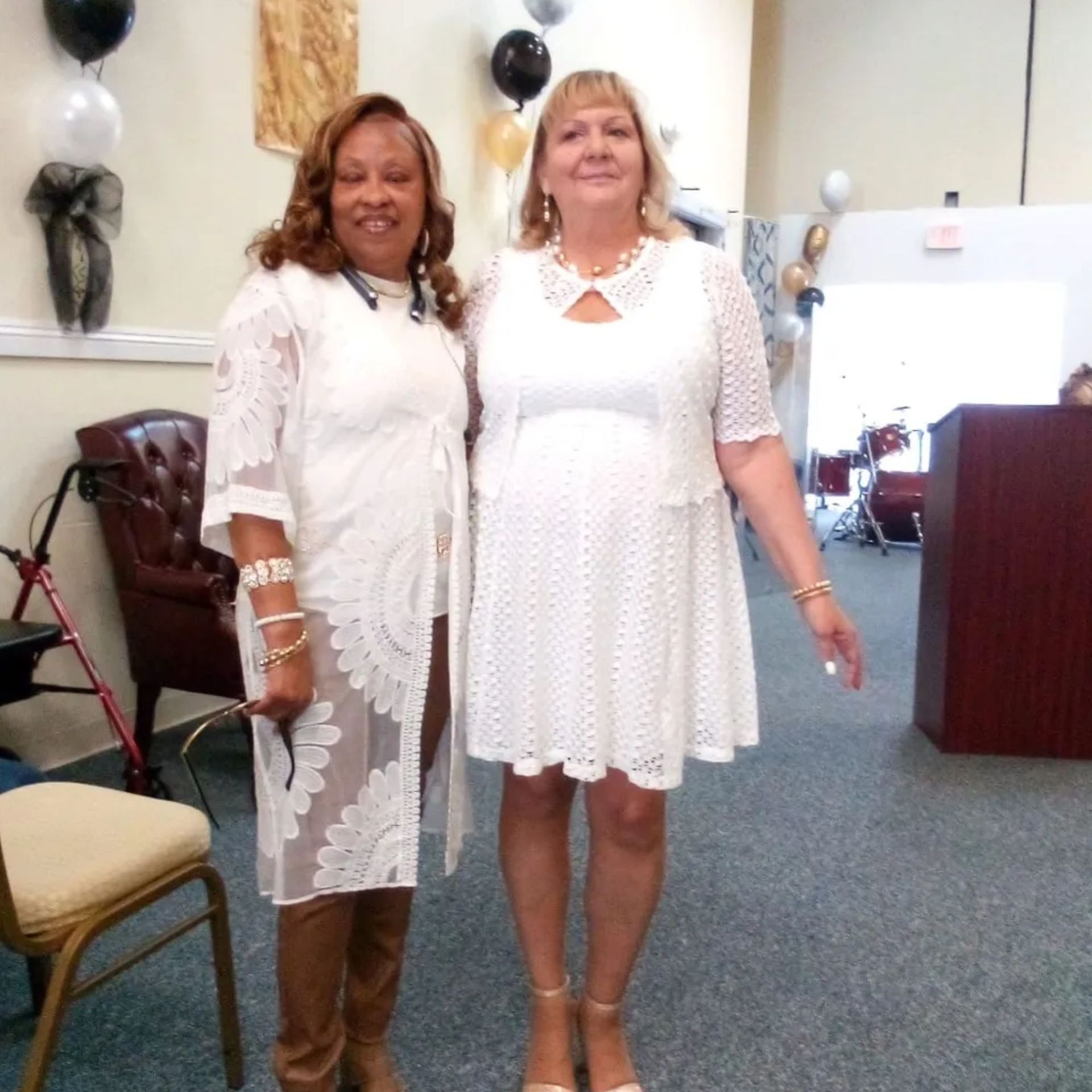 Two women standing next to each other wearing white dresses
