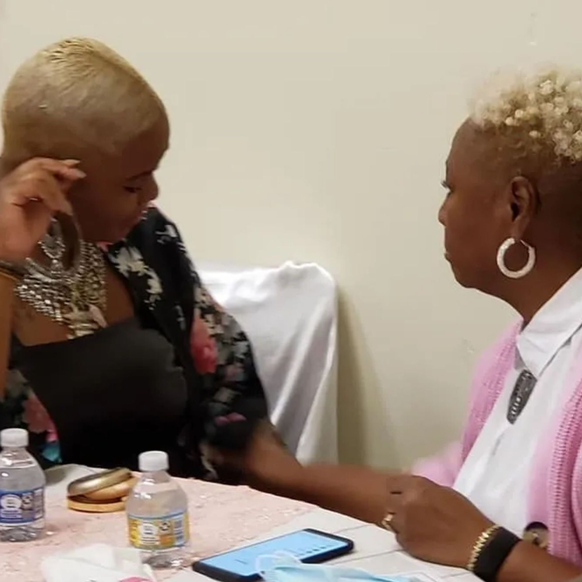 Two women are sitting at a table with a bottle of aquafina water