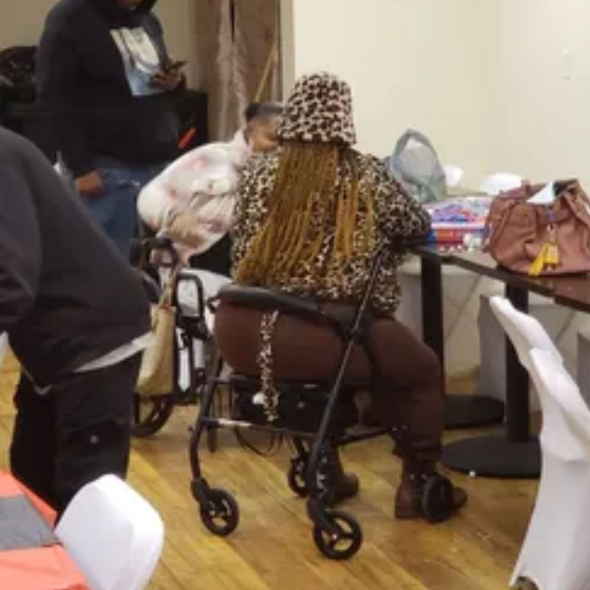 A woman in a leopard print shirt is sitting in a wheelchair.