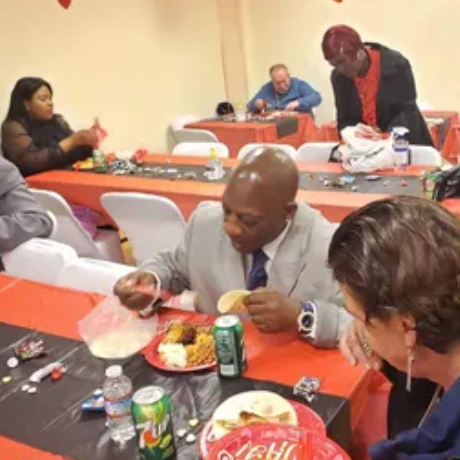A man is sitting at a table with a plate of food and a can of sprite