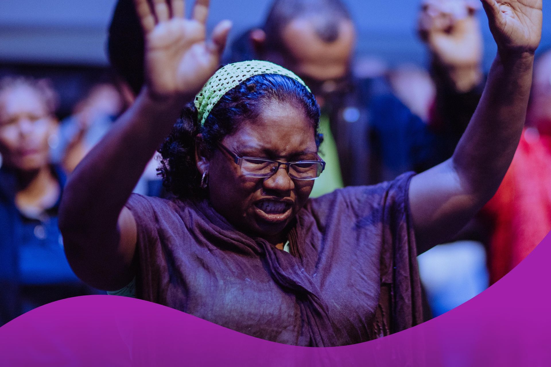 A woman is praying with her hands in the air in a church.