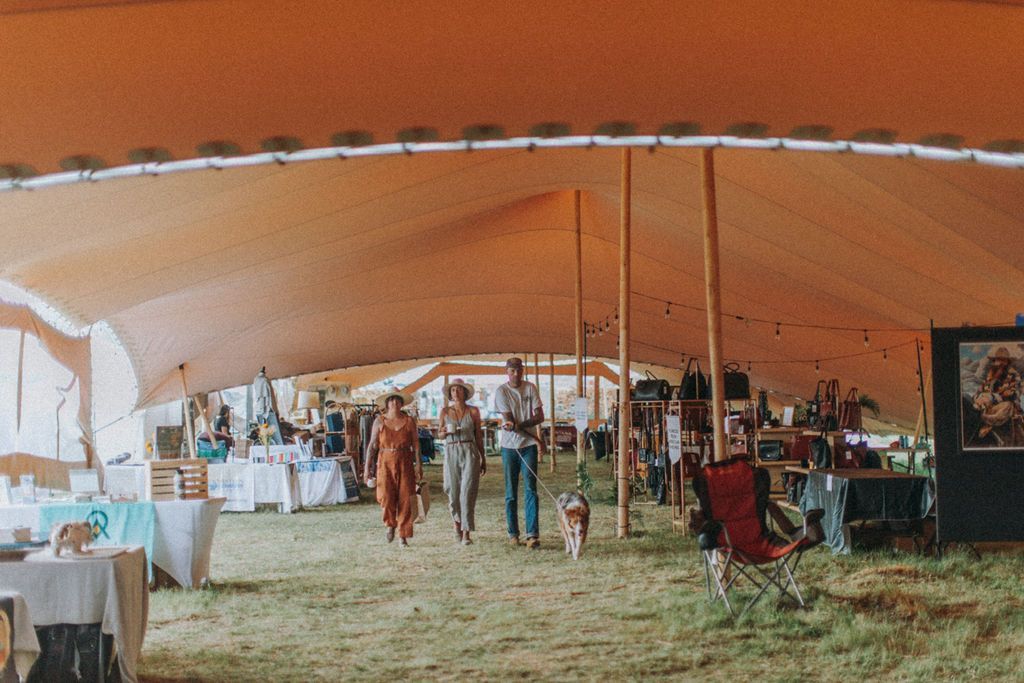 A group of people are standing under a large tent.