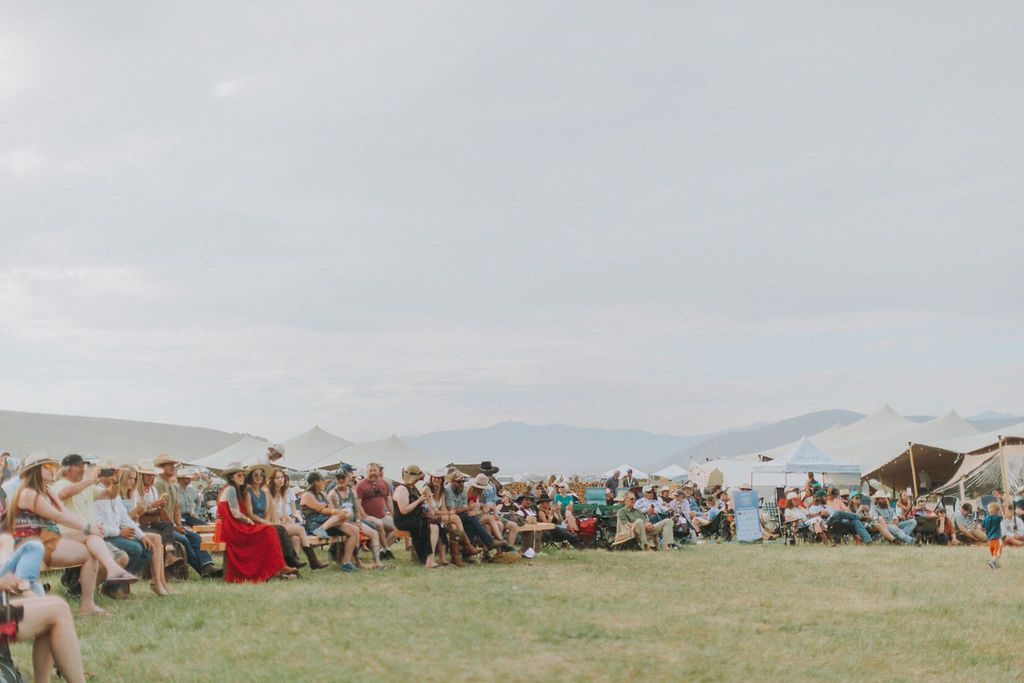 A large group of people are sitting in a field.