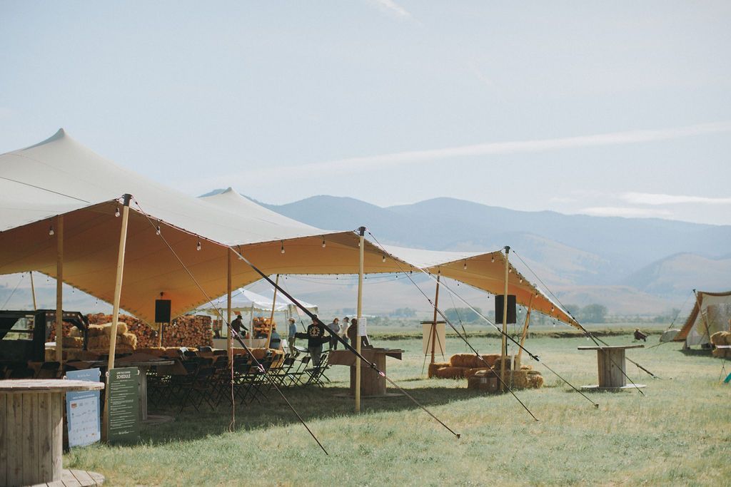 A group of tents are sitting in a field with mountains in the background.