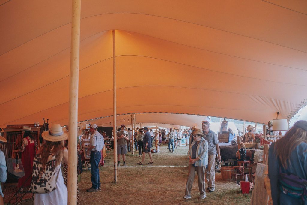 A group of people are standing under a large tent at a festival.
