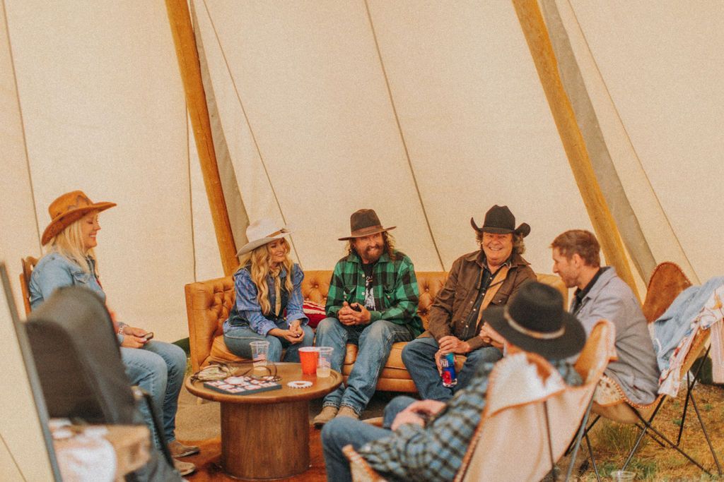 A group of people are sitting around a table in a tent.