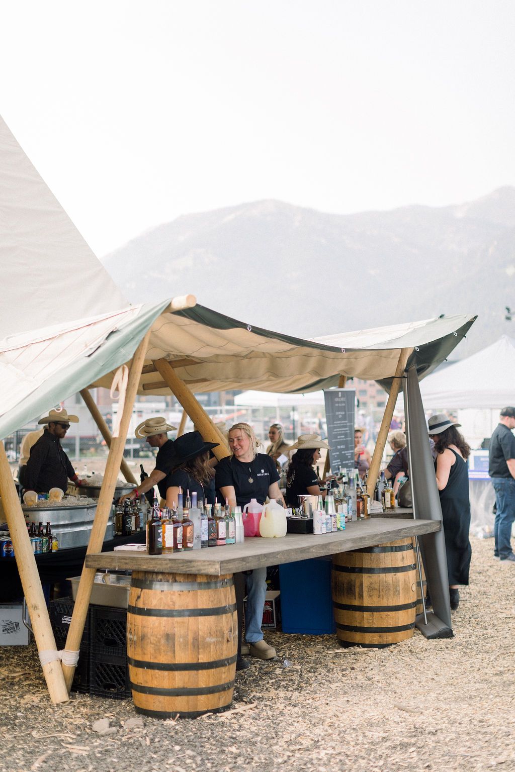 A group of people are standing around a table with barrels on it.