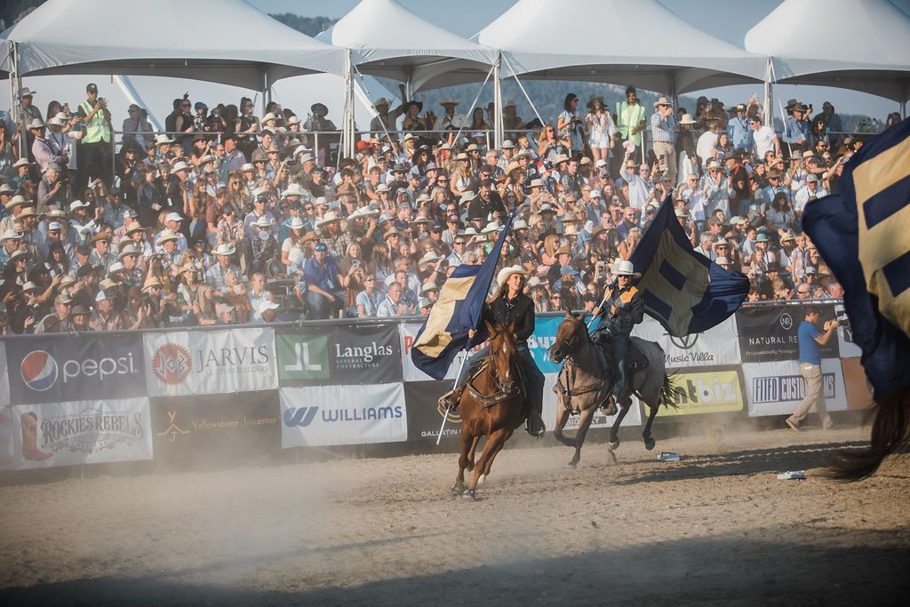 A man is riding a horse in front of a crowd at a rodeo.