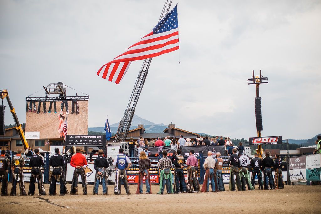 A group of people are standing in front of a large american flag.