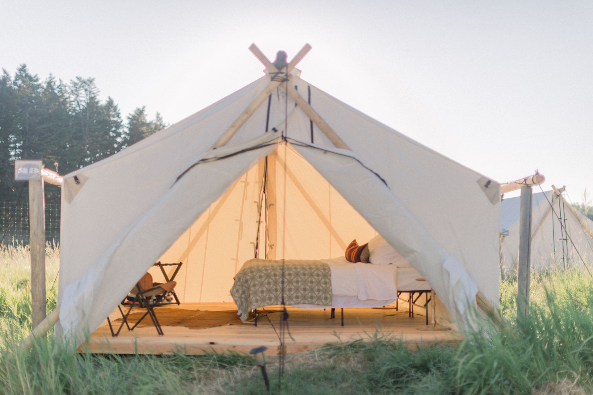 A tent with a bed inside of it in a field.