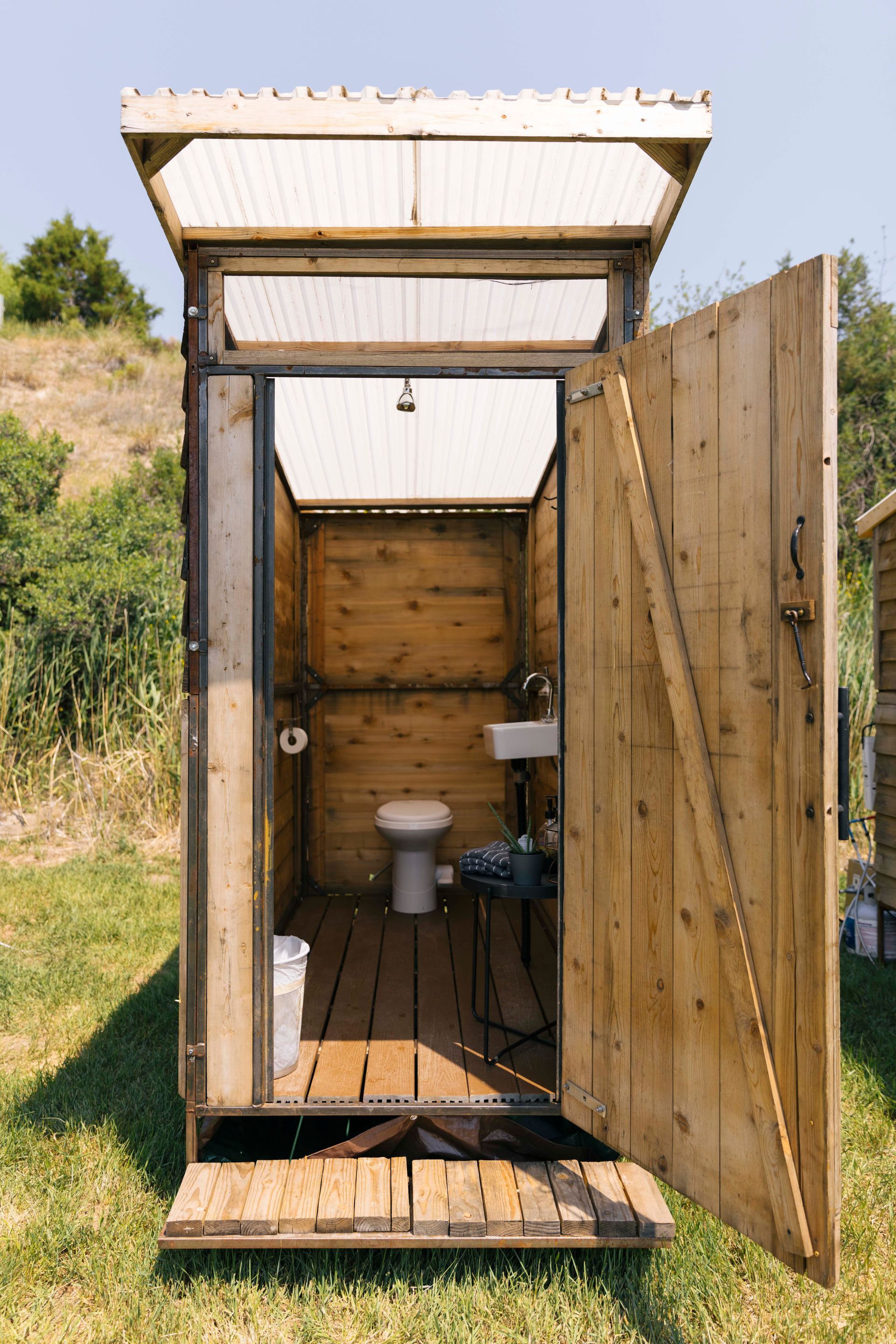A wooden outhouse with a toilet and sink inside of it.