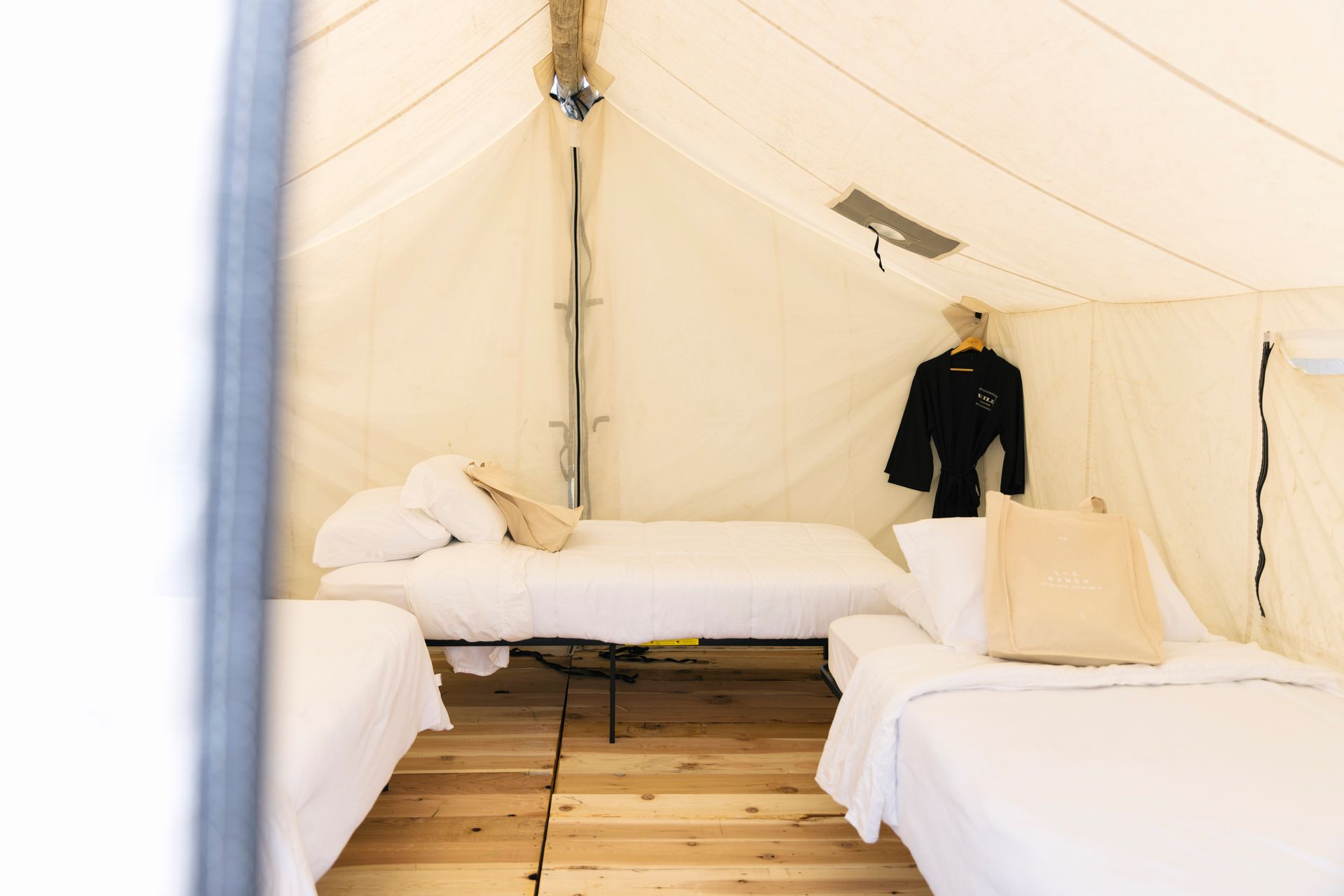 There are three beds in a tent with a wooden floor.