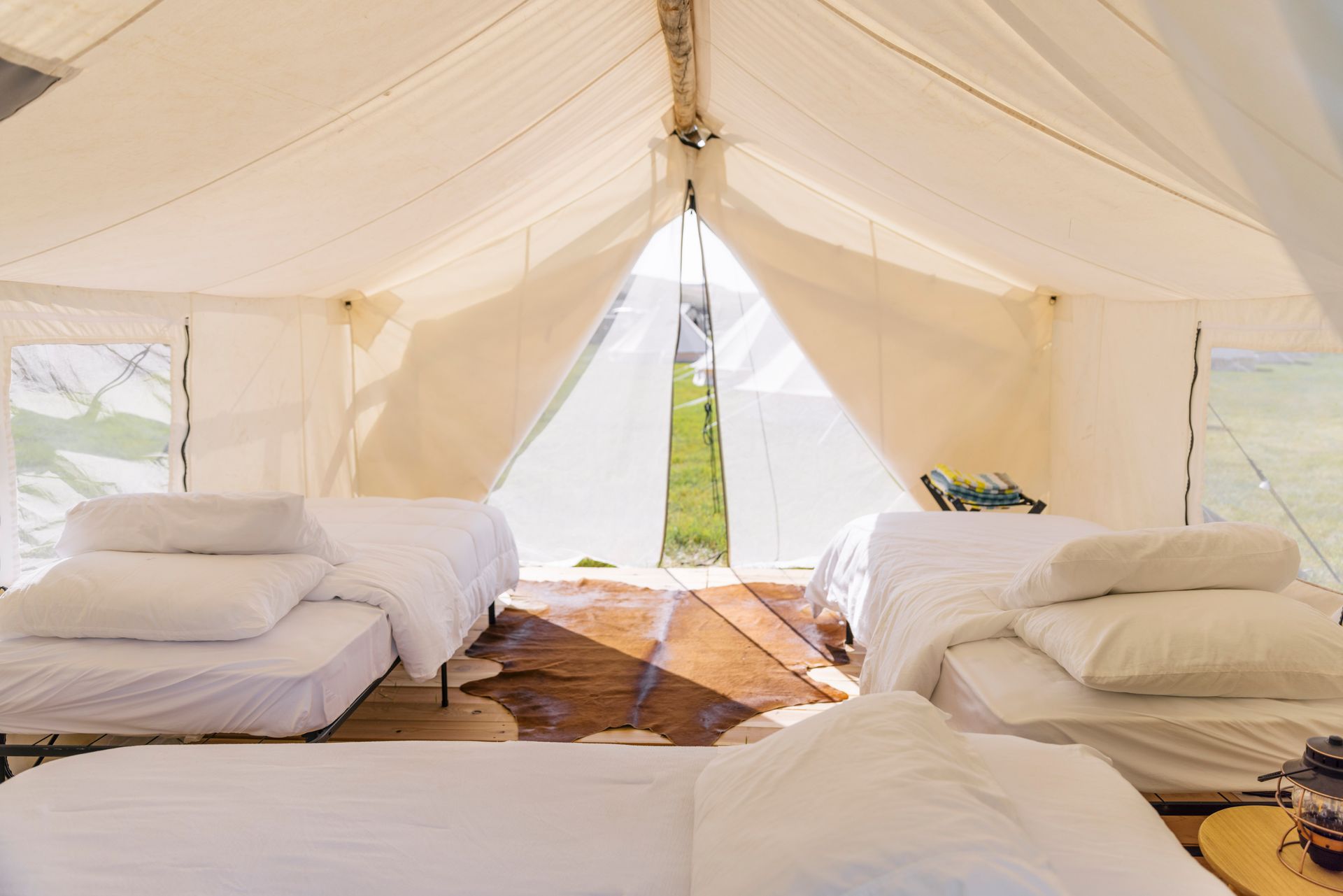 A tent with three beds and a table inside of it.