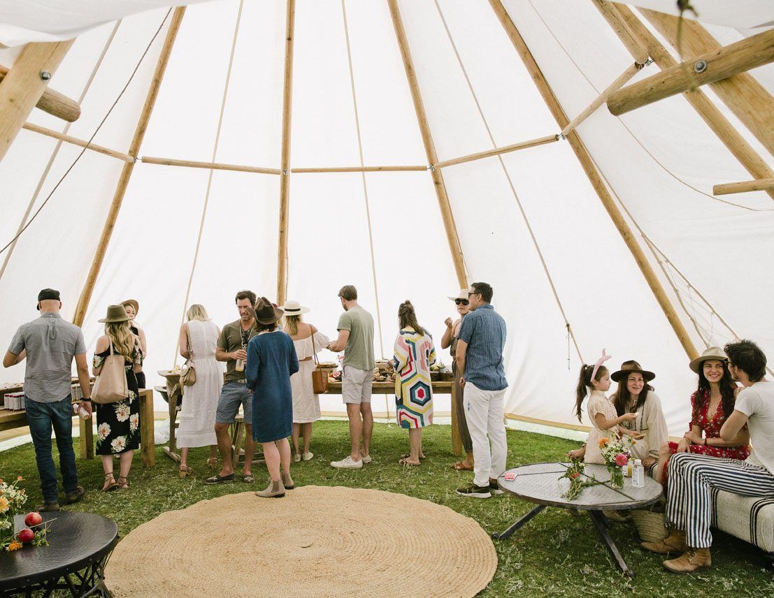 A group of people are standing inside of a teepee.