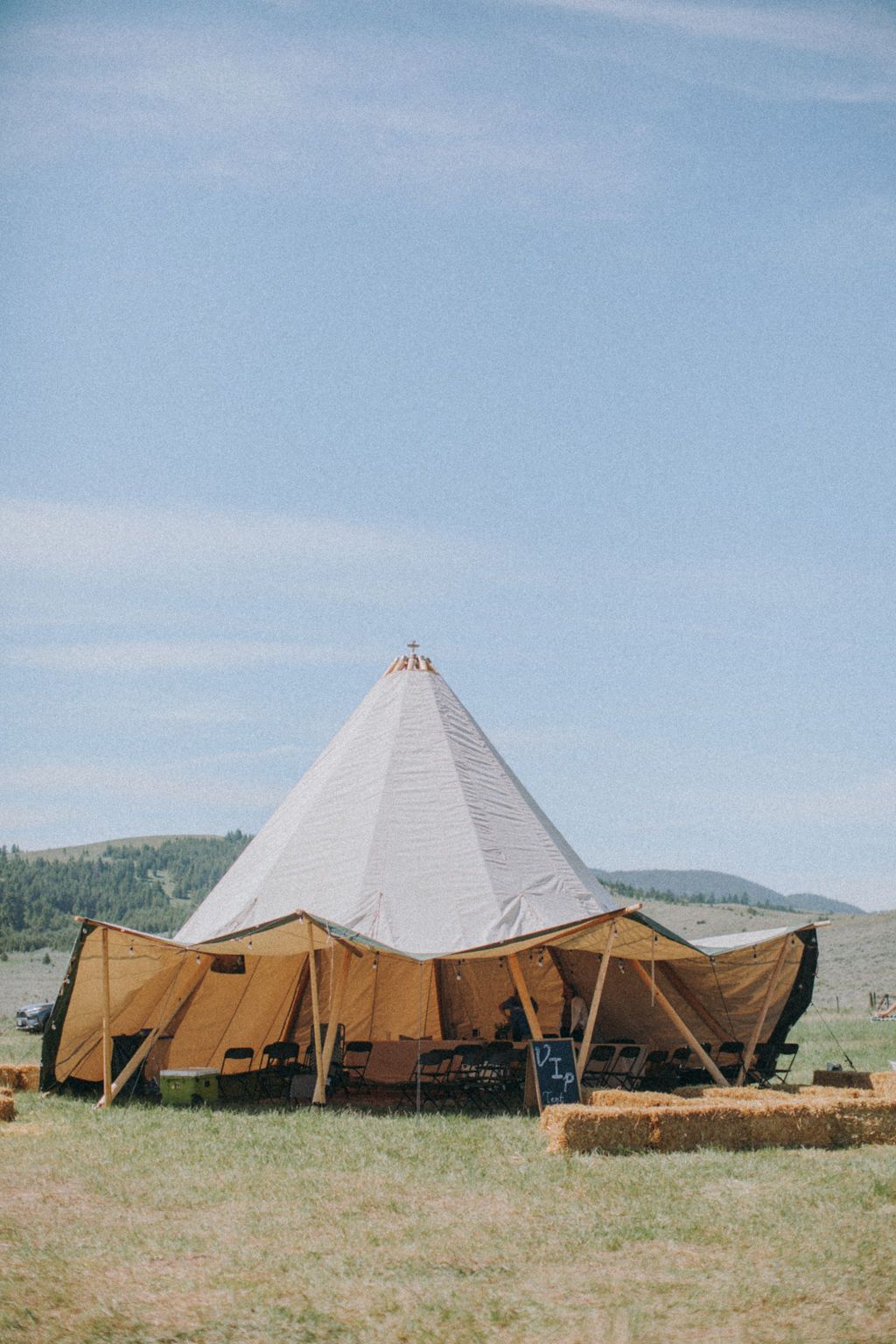 A large tent is sitting in the middle of a grassy field.