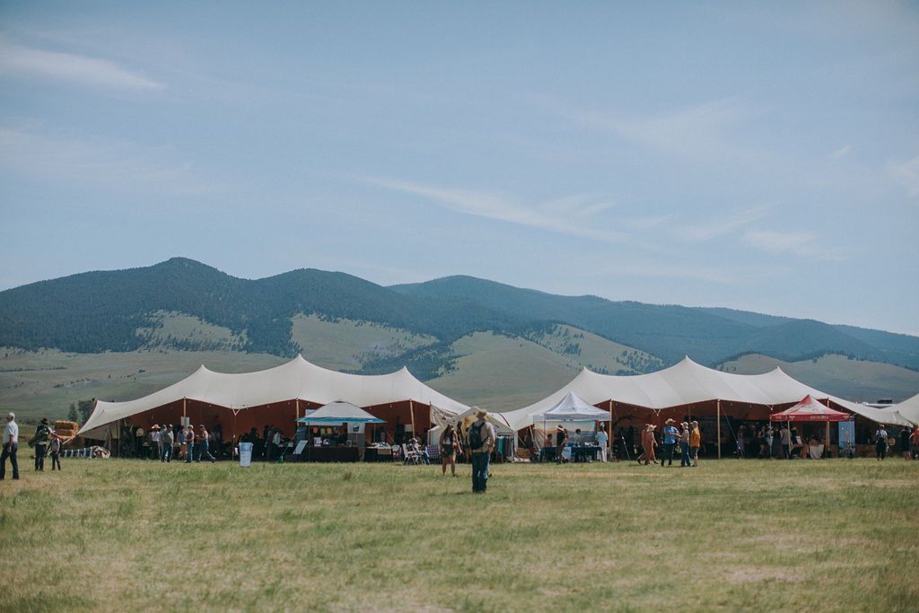 A row of tents in a field with mountains in the background.