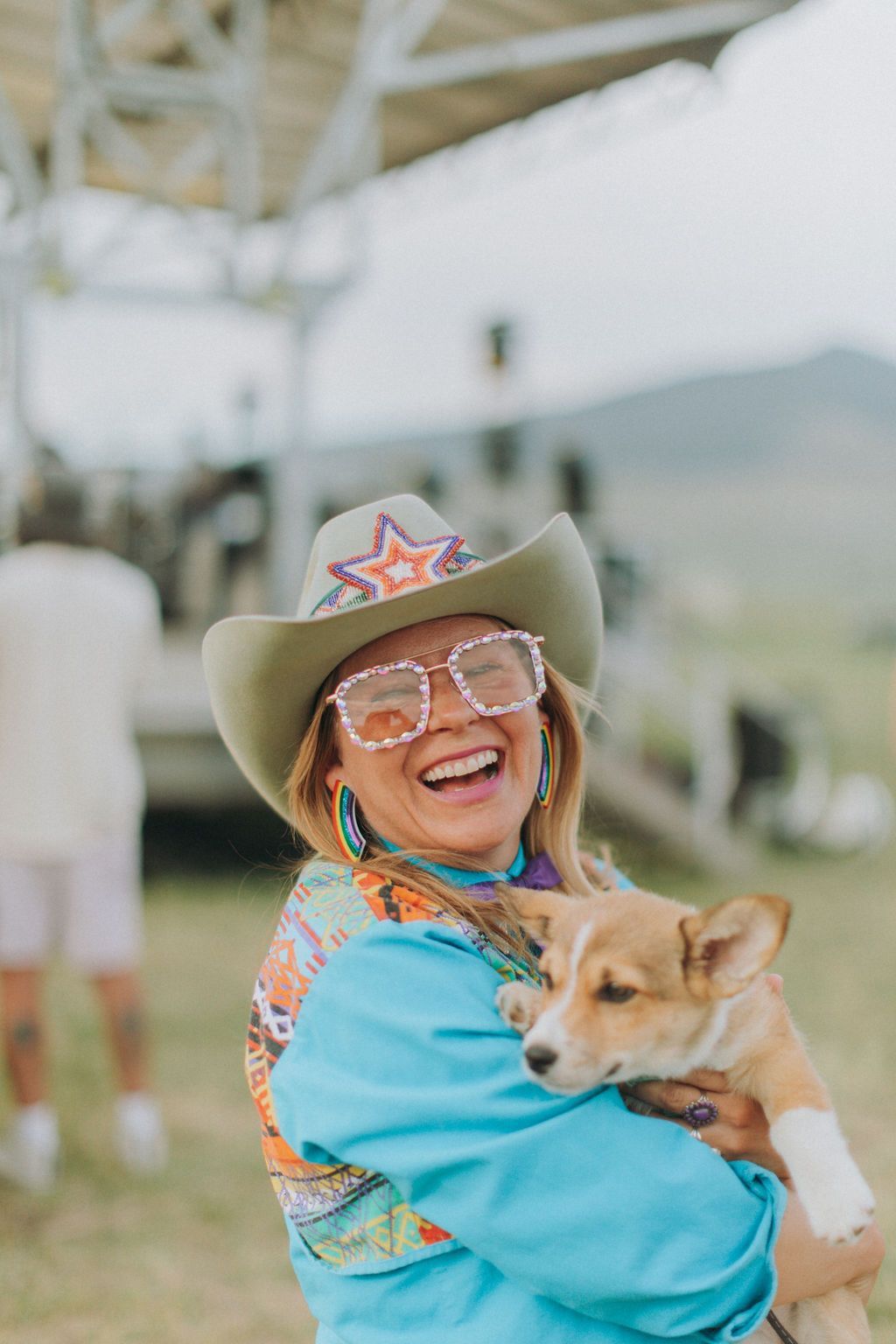 A woman in a cowboy hat is holding a dog in her arms.