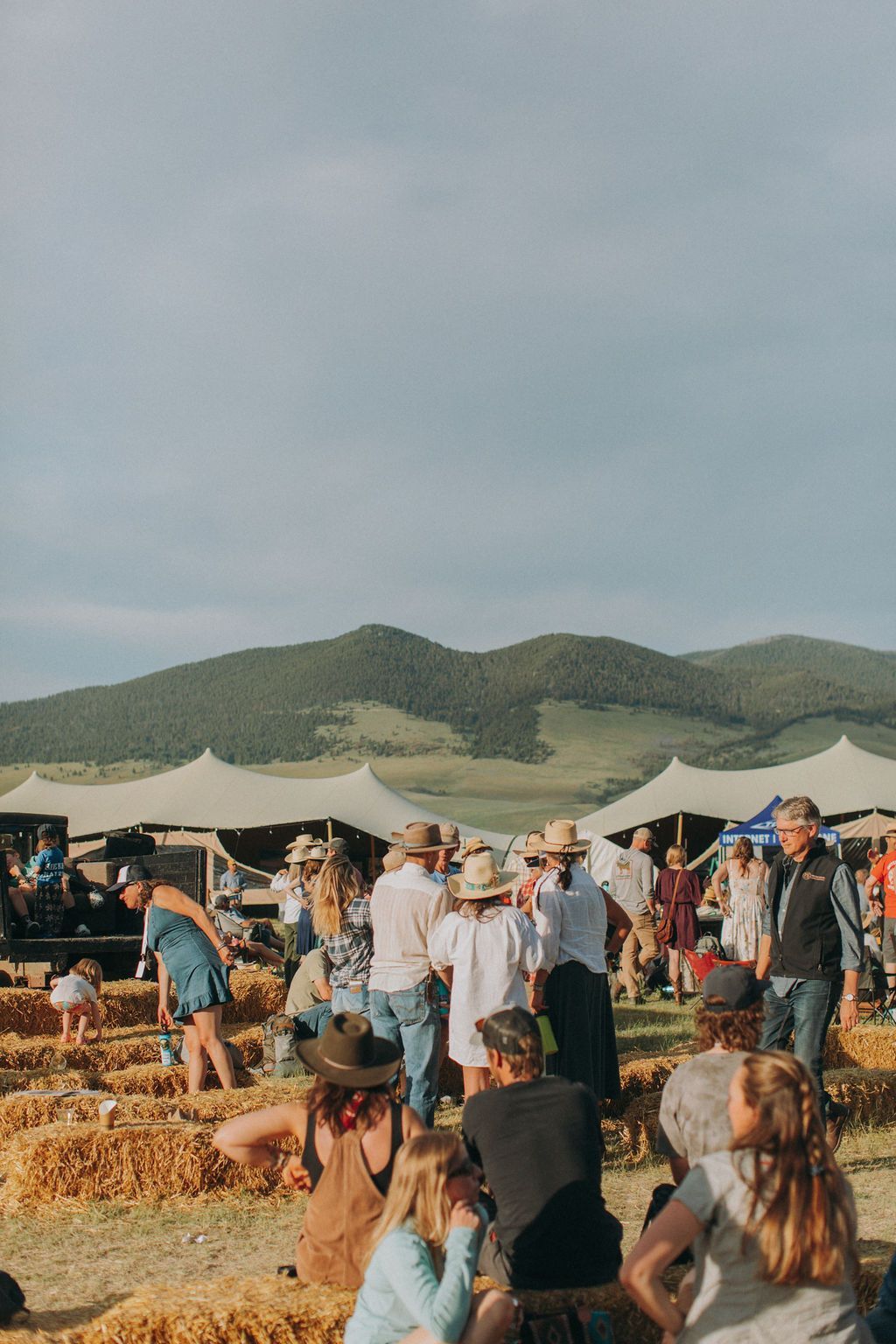 A group of people are gathered in a field with mountains in the background.