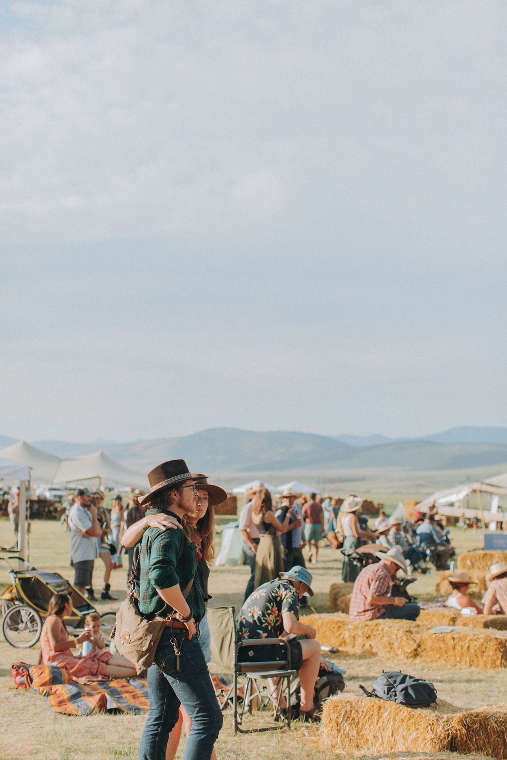 A group of people are standing around hay bales in a field.
