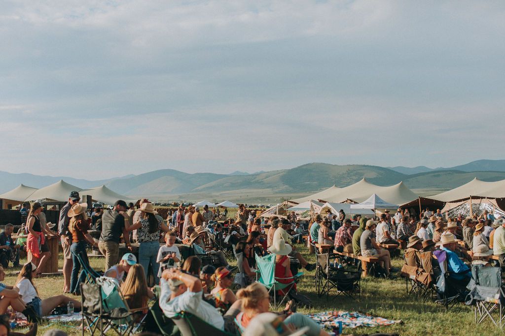 A large group of people are sitting in chairs in a field.