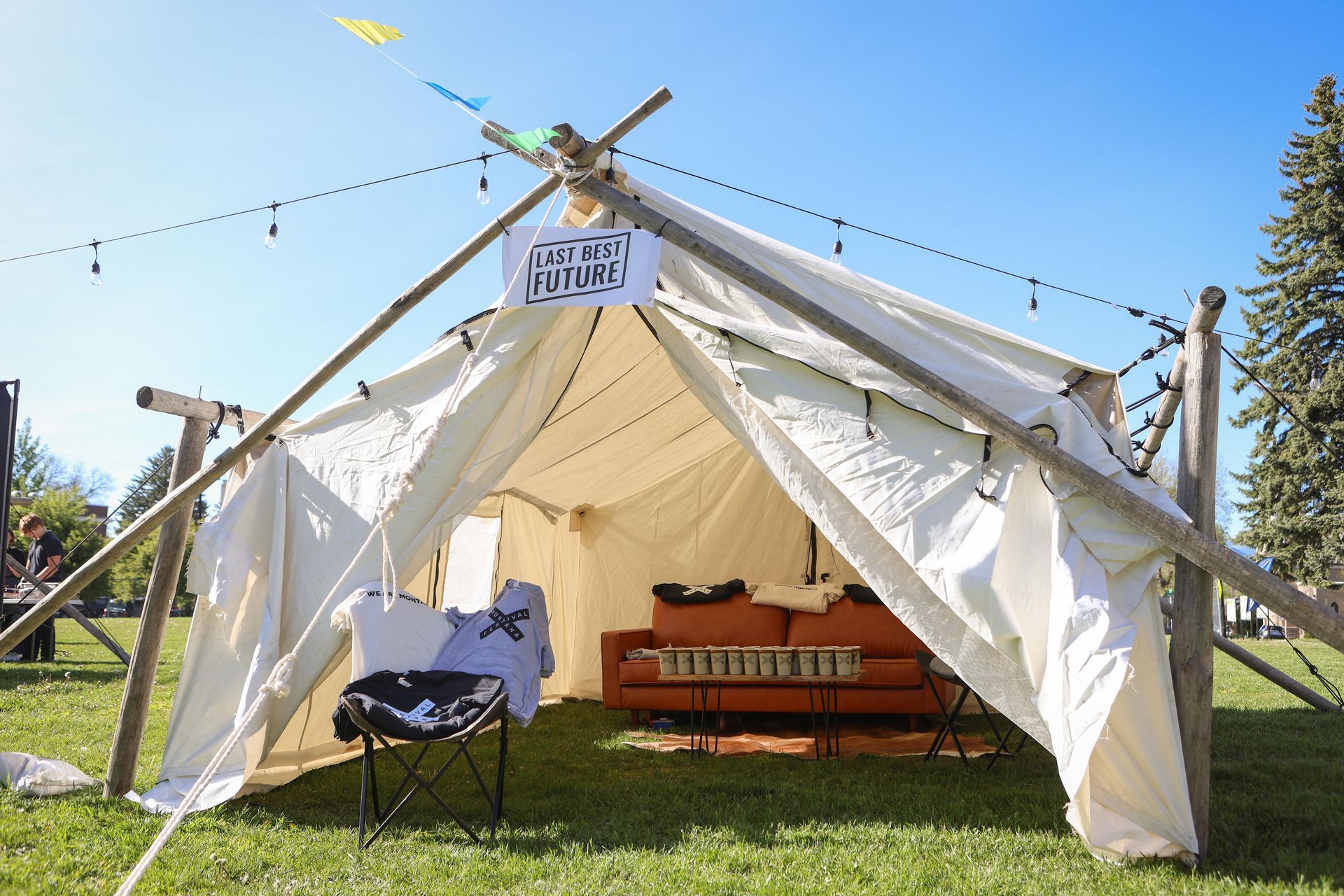 A white tent with a couch inside of it in a grassy field.