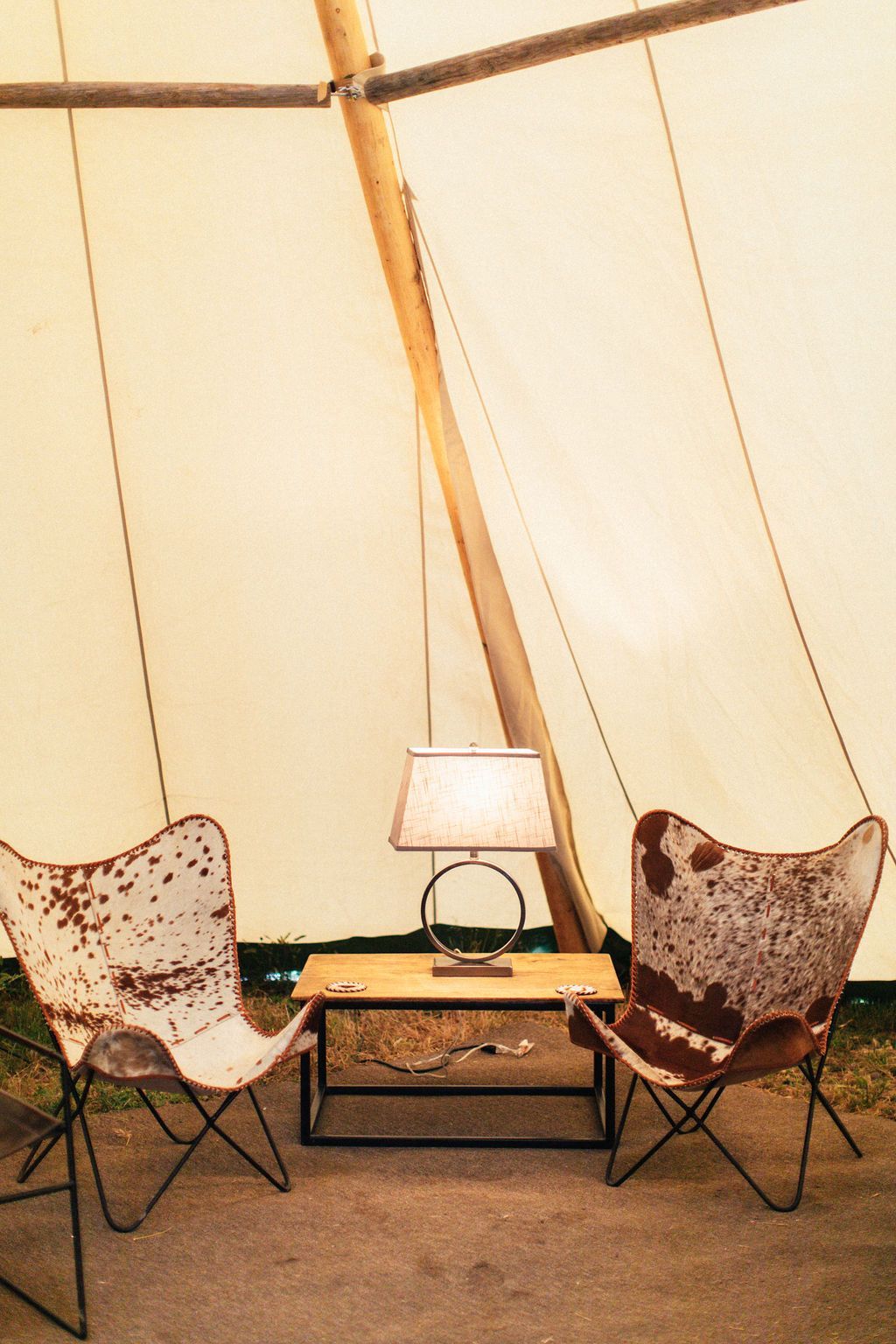 Two chairs are sitting next to a table in a tent.