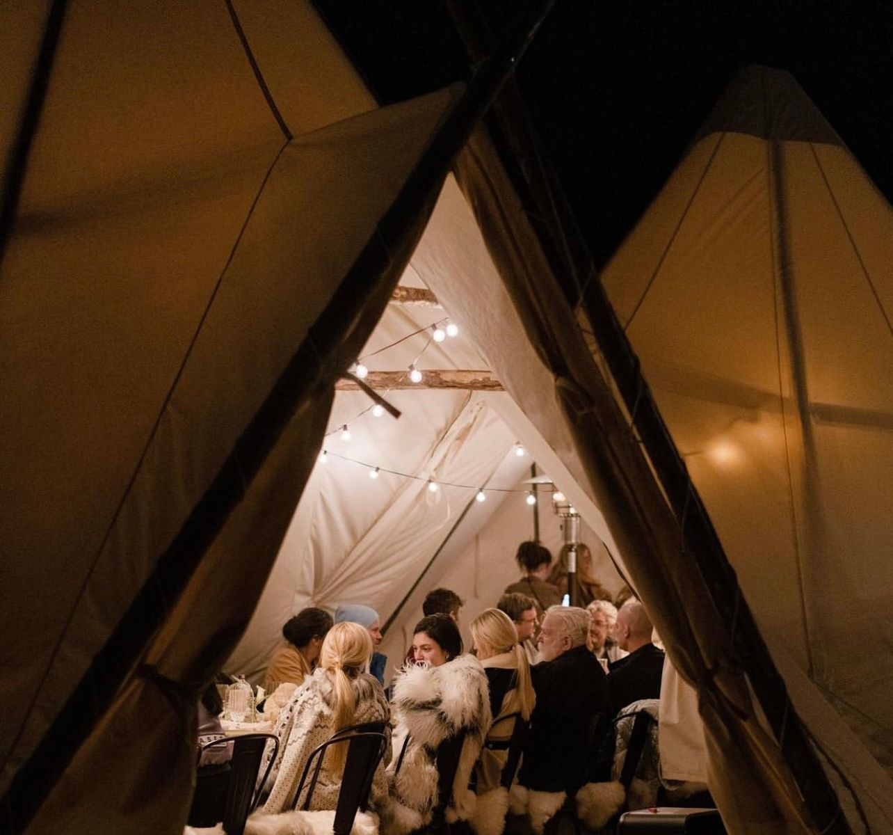 A group of people are gathered in a tent at night