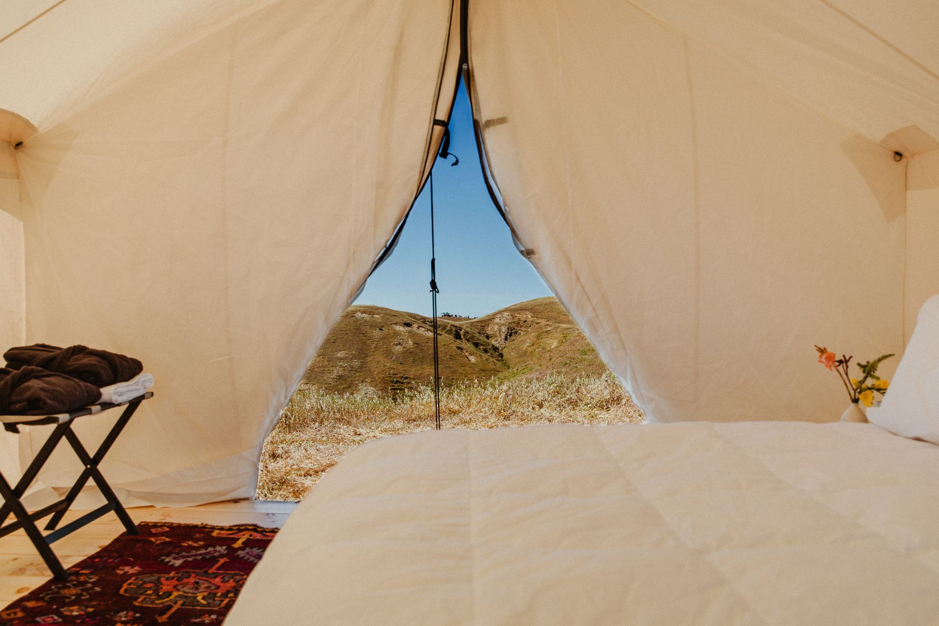 A bed in a tent with a view of the desert.