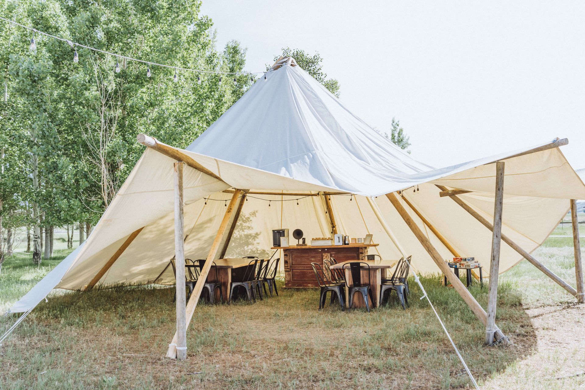 A large tent with tables and chairs inside of it in a field.