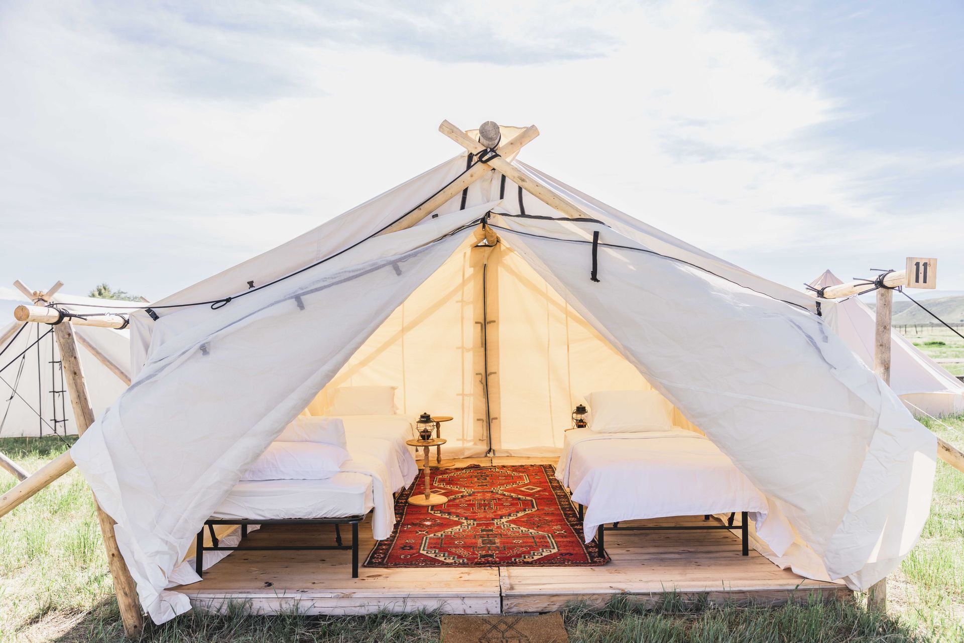 A tent with two beds inside of it is sitting in the middle of a field.