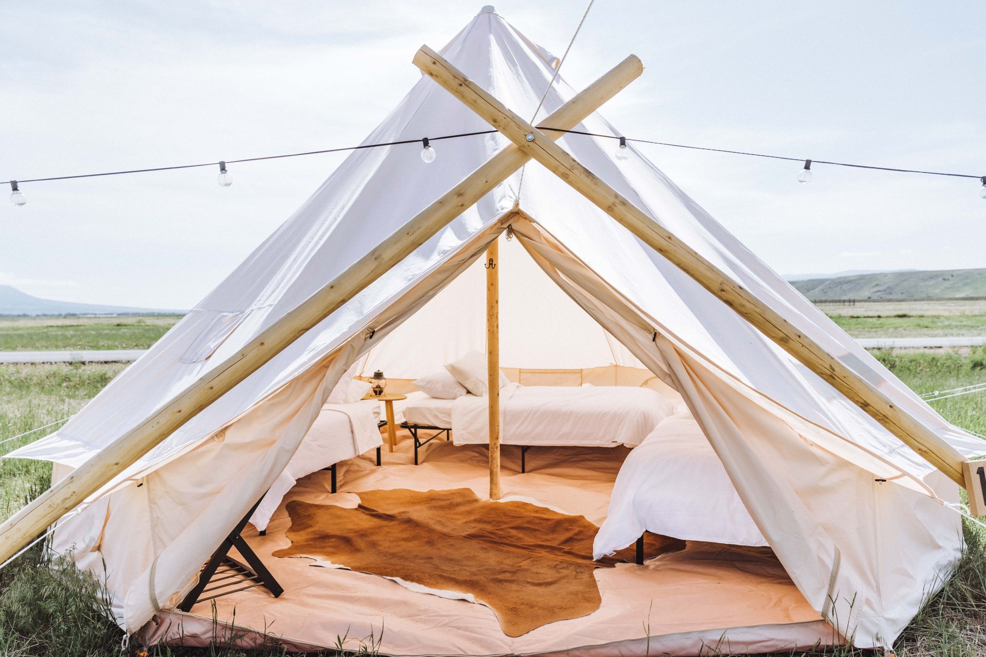 A tent with two beds inside of it in a field.