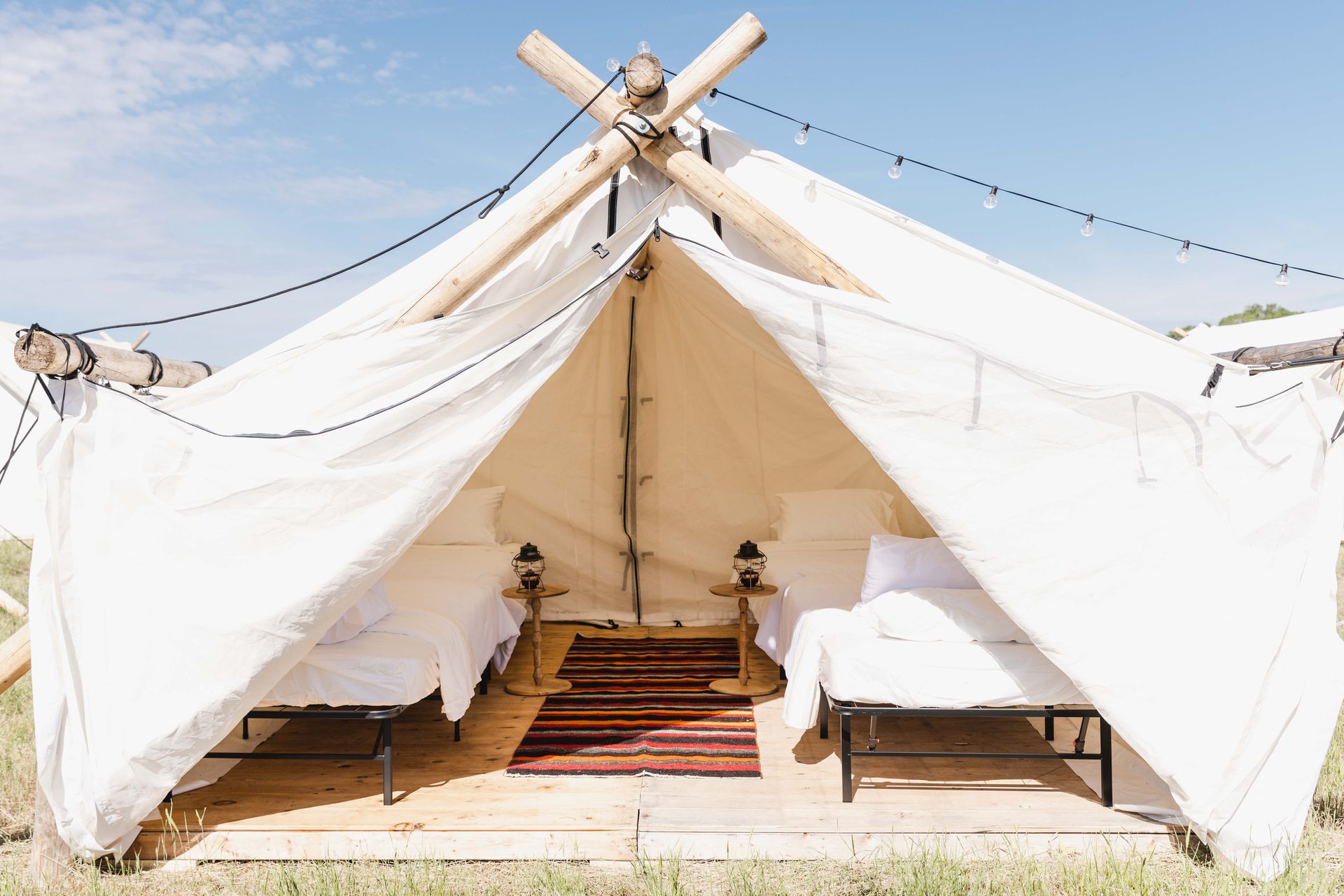 A white tent with two beds inside of it in a field.