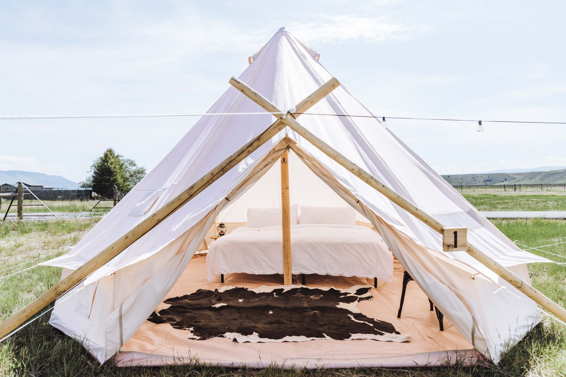 A tent with two beds and a cowhide rug inside of it.