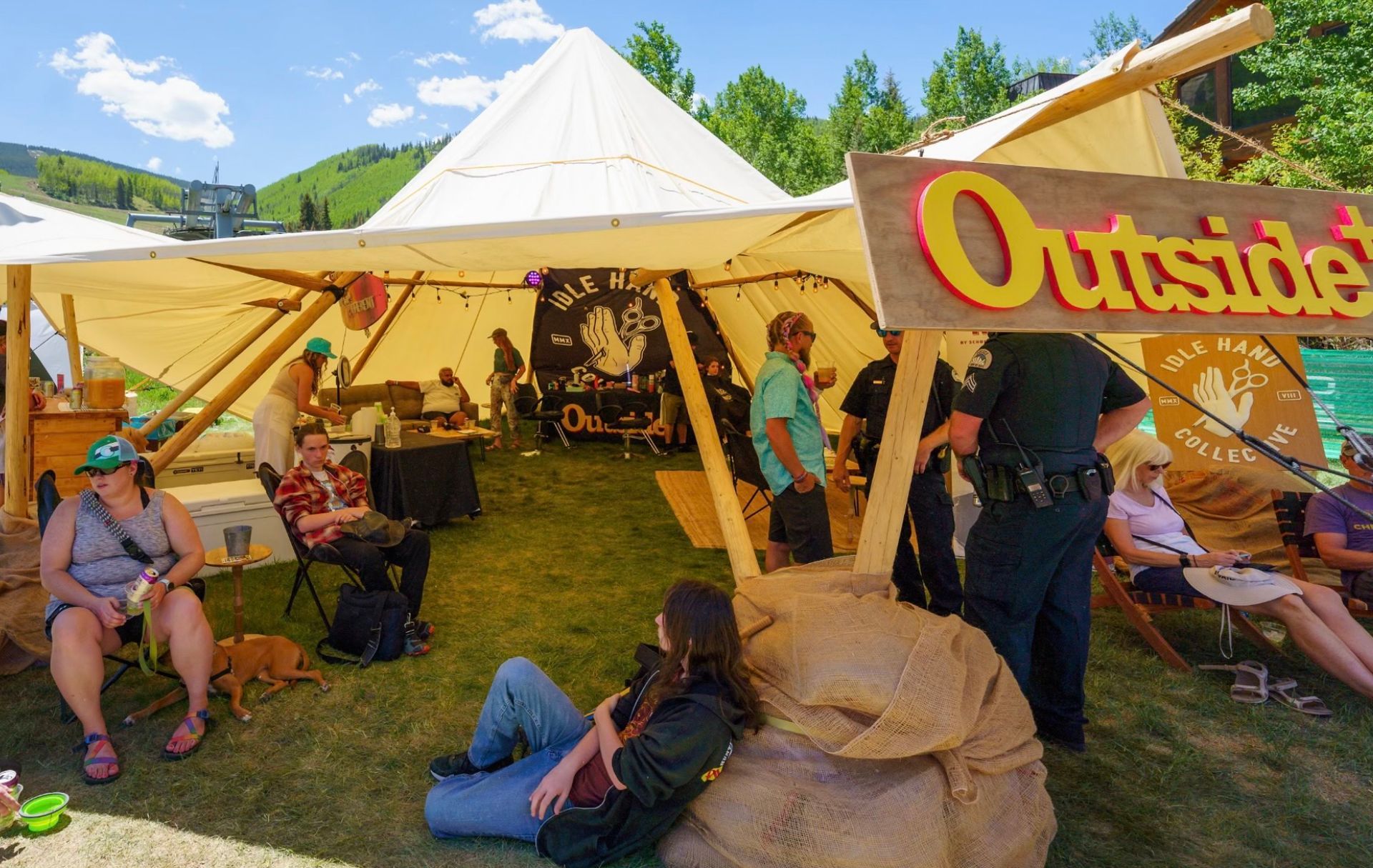 A group of people sitting under a tent with a sign that says outside