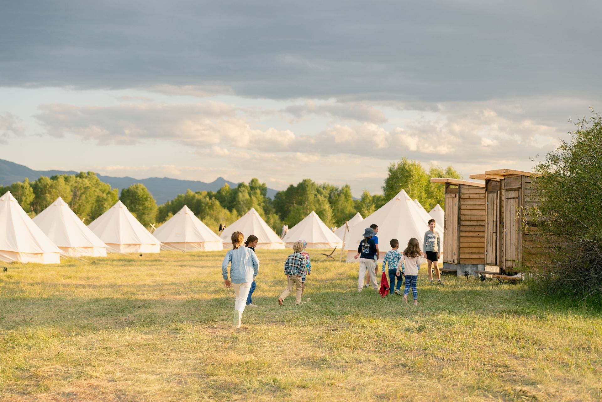 A group of people are walking in a field with tents in the background.