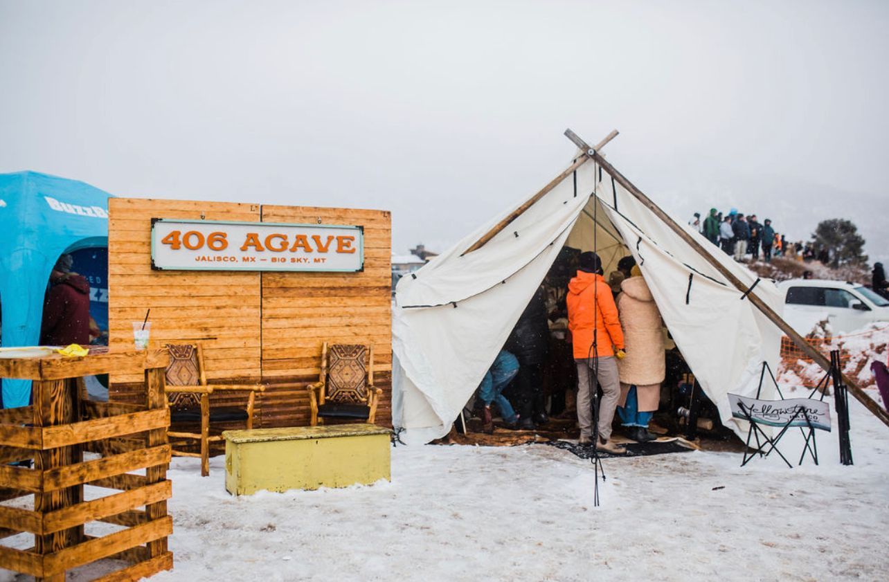 A group of people are standing in front of a tent that says 408 agave.