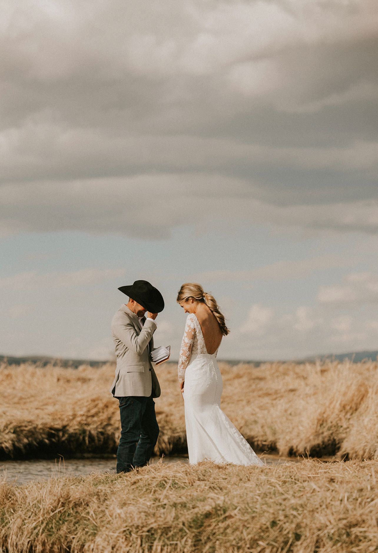 A bride and groom are standing next to each other in a field.