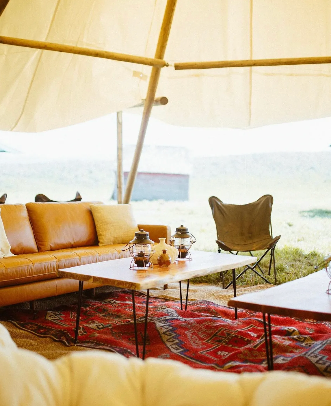 A living room with a couch , table and chairs in a tent.