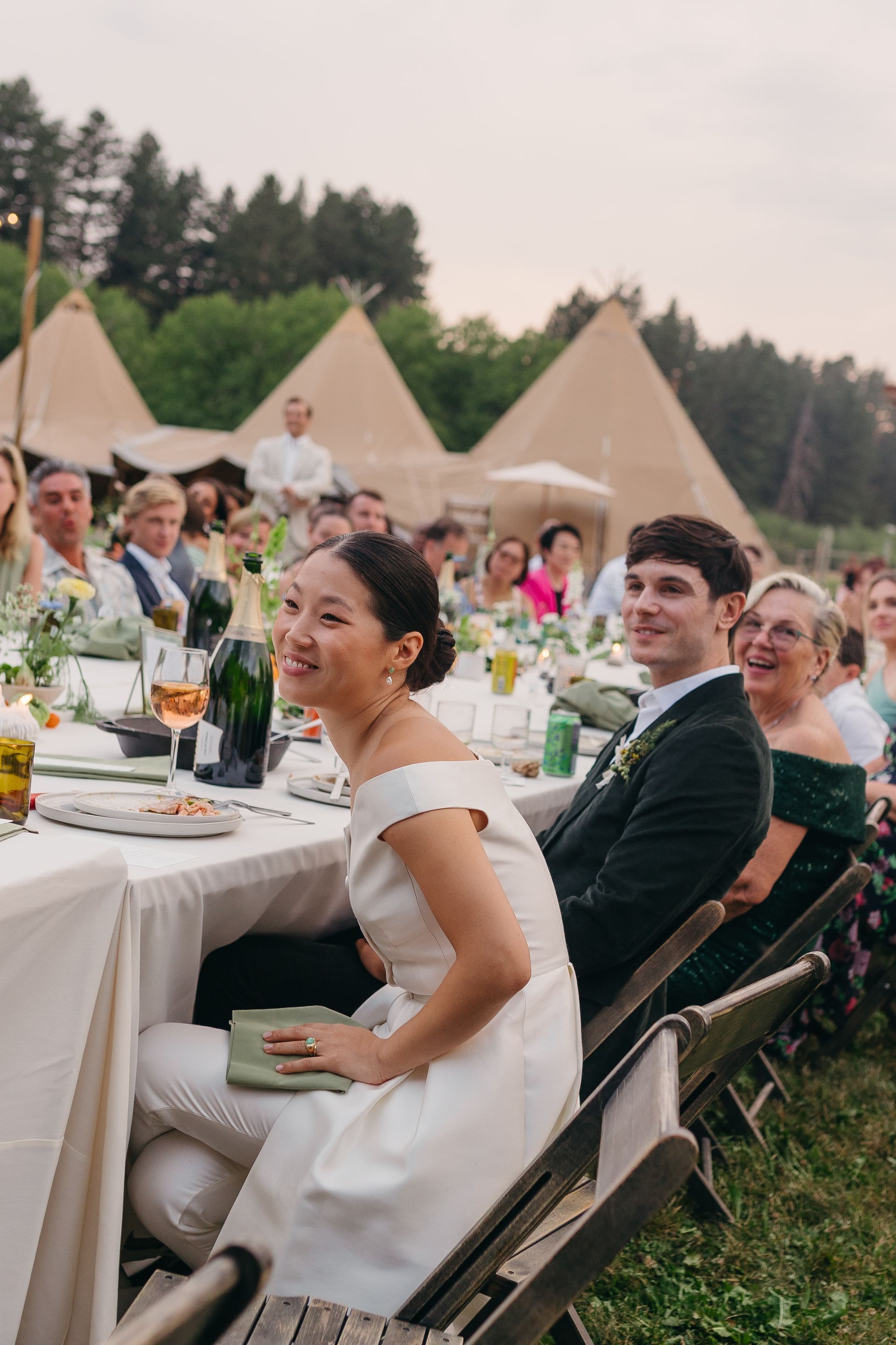 A bride and groom are sitting at a table at a wedding reception.