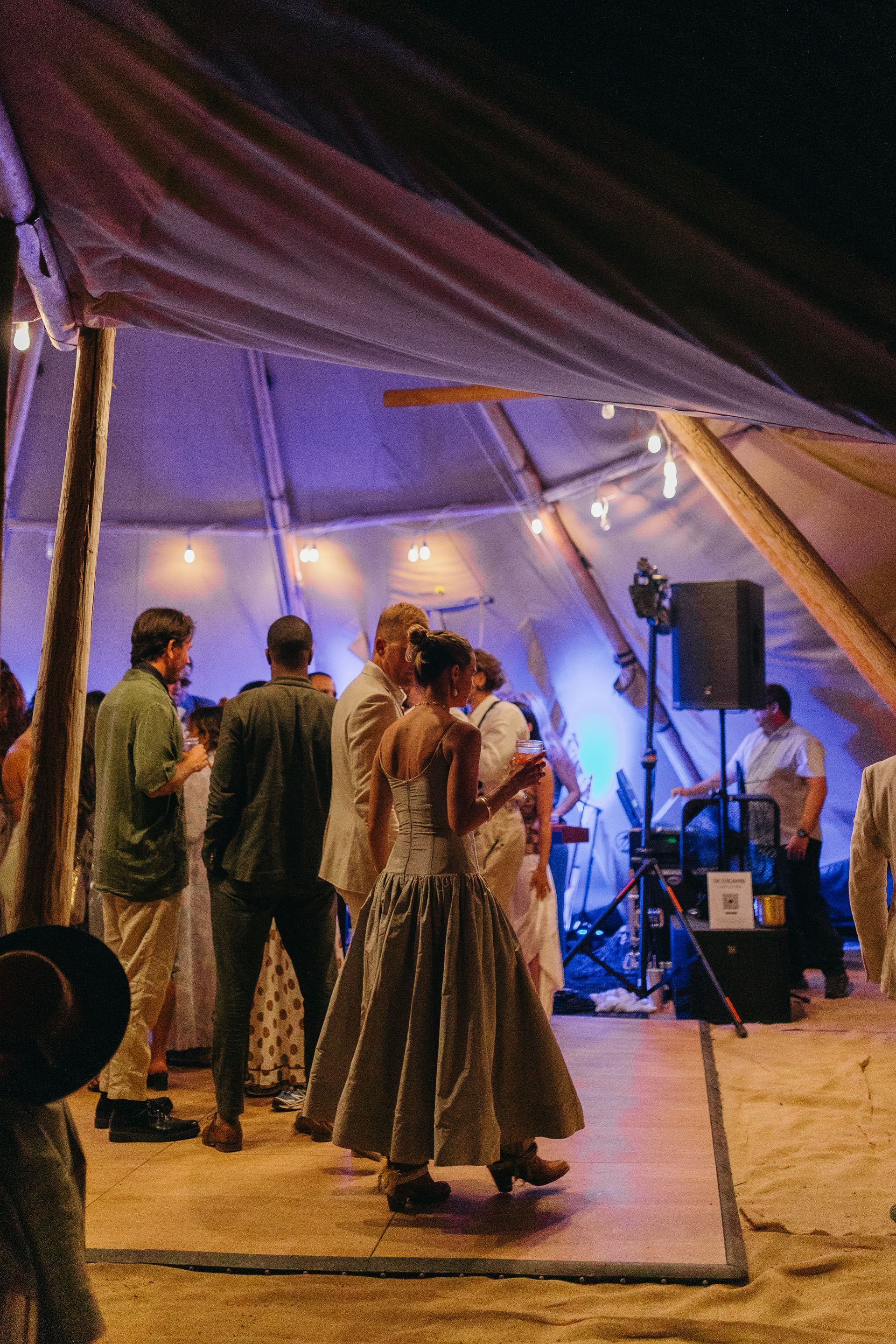 A group of people are dancing in a tent at night.