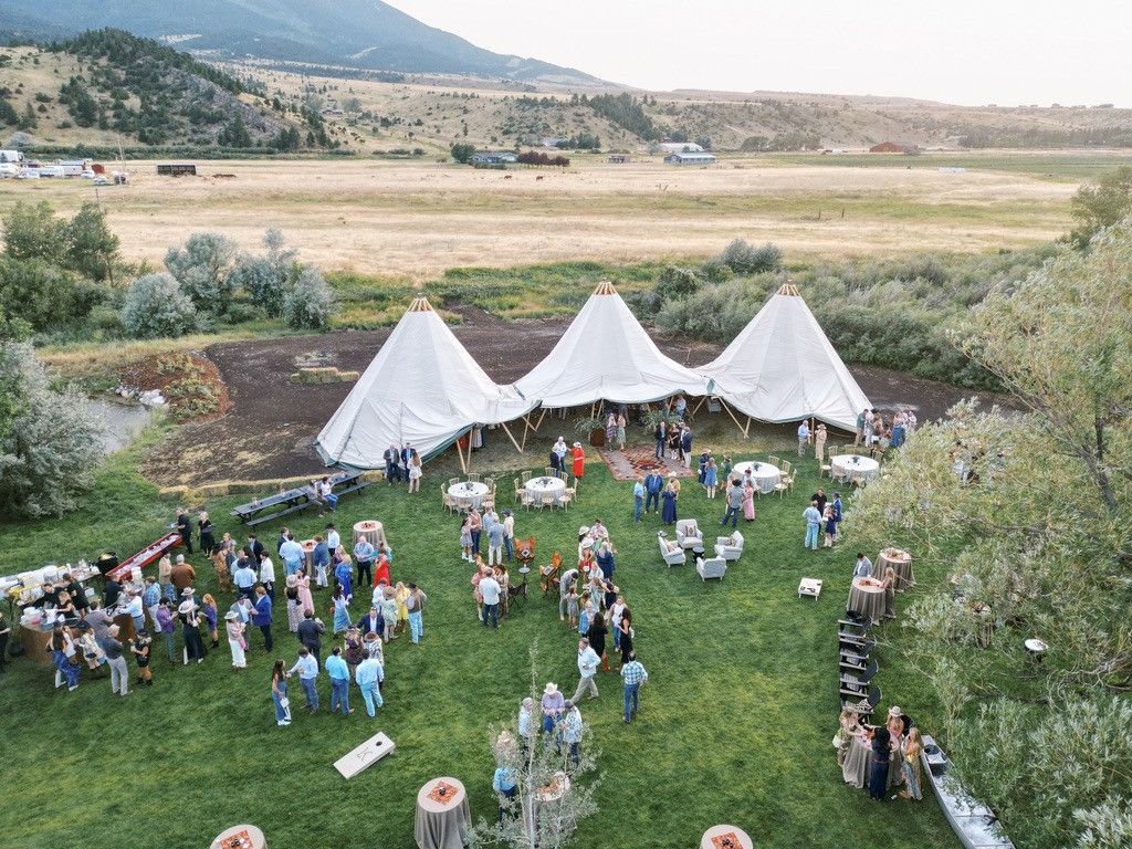 An aerial view of a large group of people standing under tents in a grassy field.