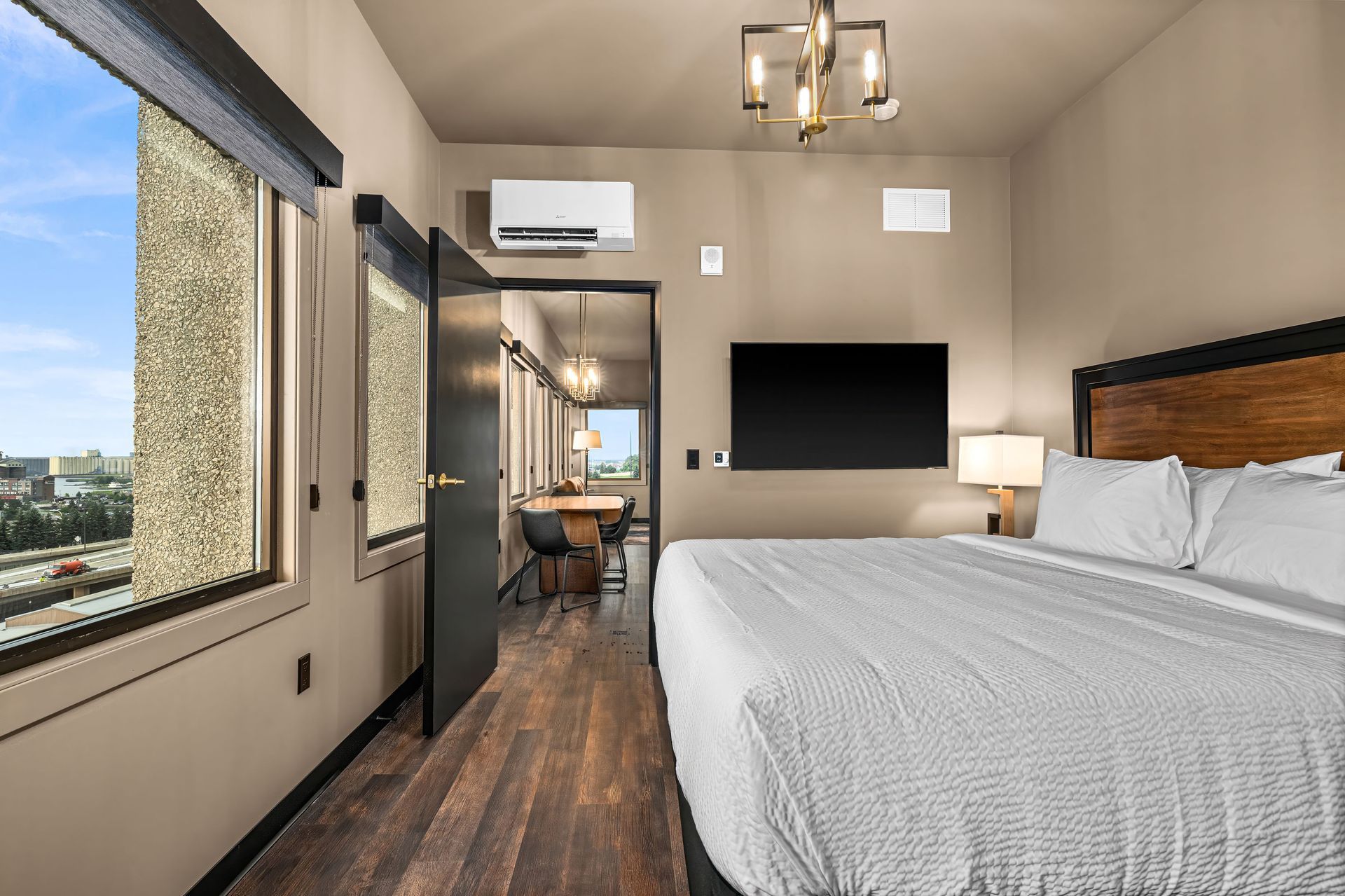 A bedroom with a bed , dresser , and two windows.