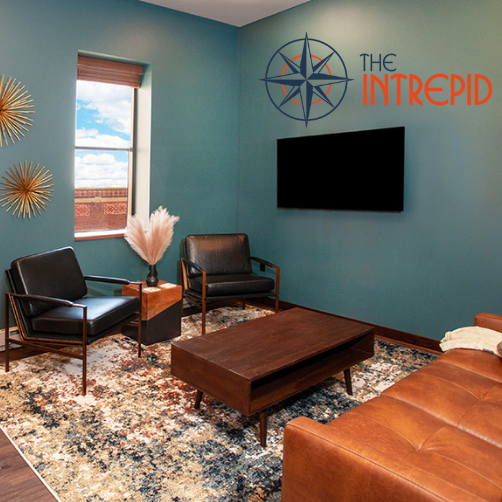 A living room with a couch , chairs , coffee table and television.