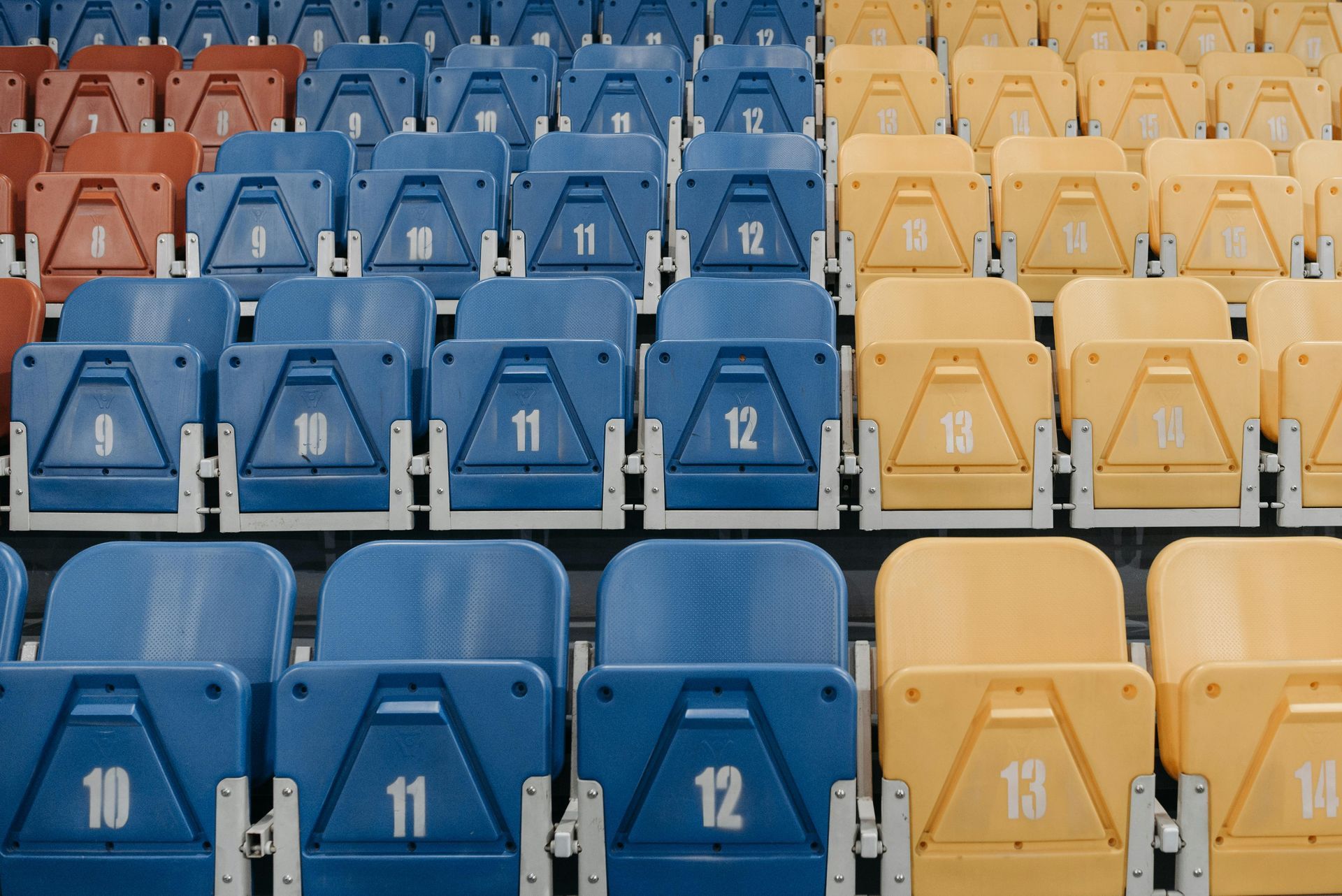 A row of blue and yellow stadium seats with numbers on them